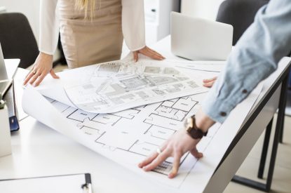 Construction workers looking at a project plan on a table.